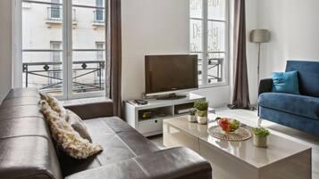 Een moderne woonkamer met een bank, salontafel, televisie en uitzicht op een balkon.