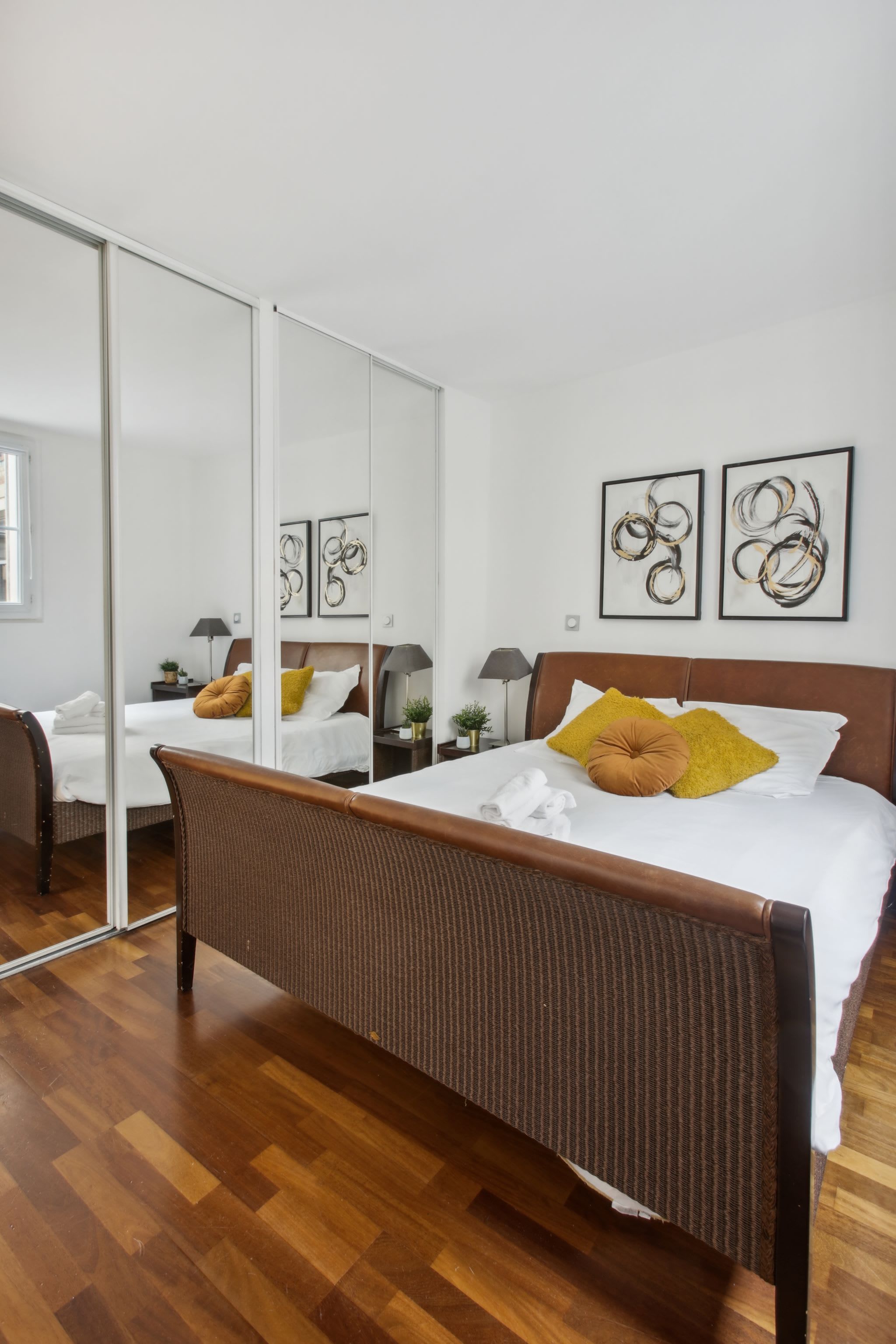 Una habitación de hotel moderna con una cama grande, un espejo y obras de arte en las paredes.