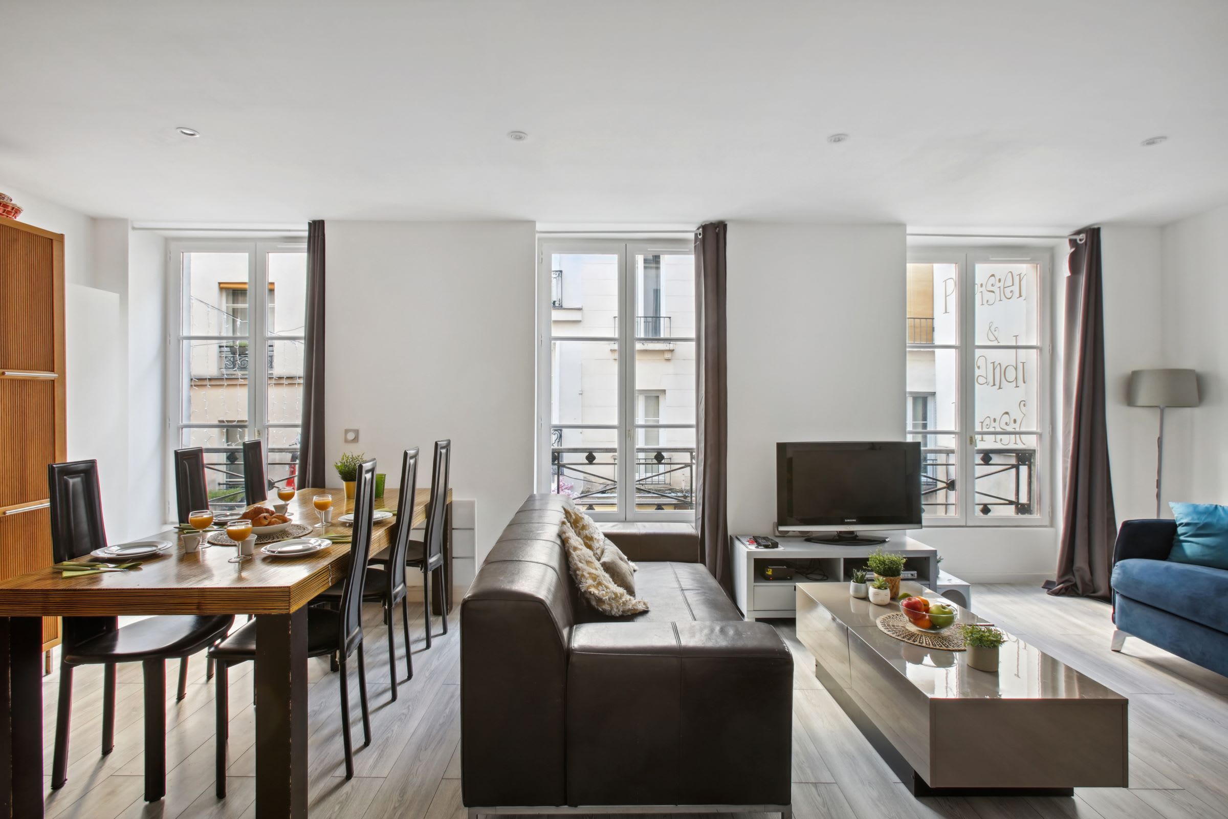 Uma sala de estar moderna com sofá, mesa de jantar e televisão.