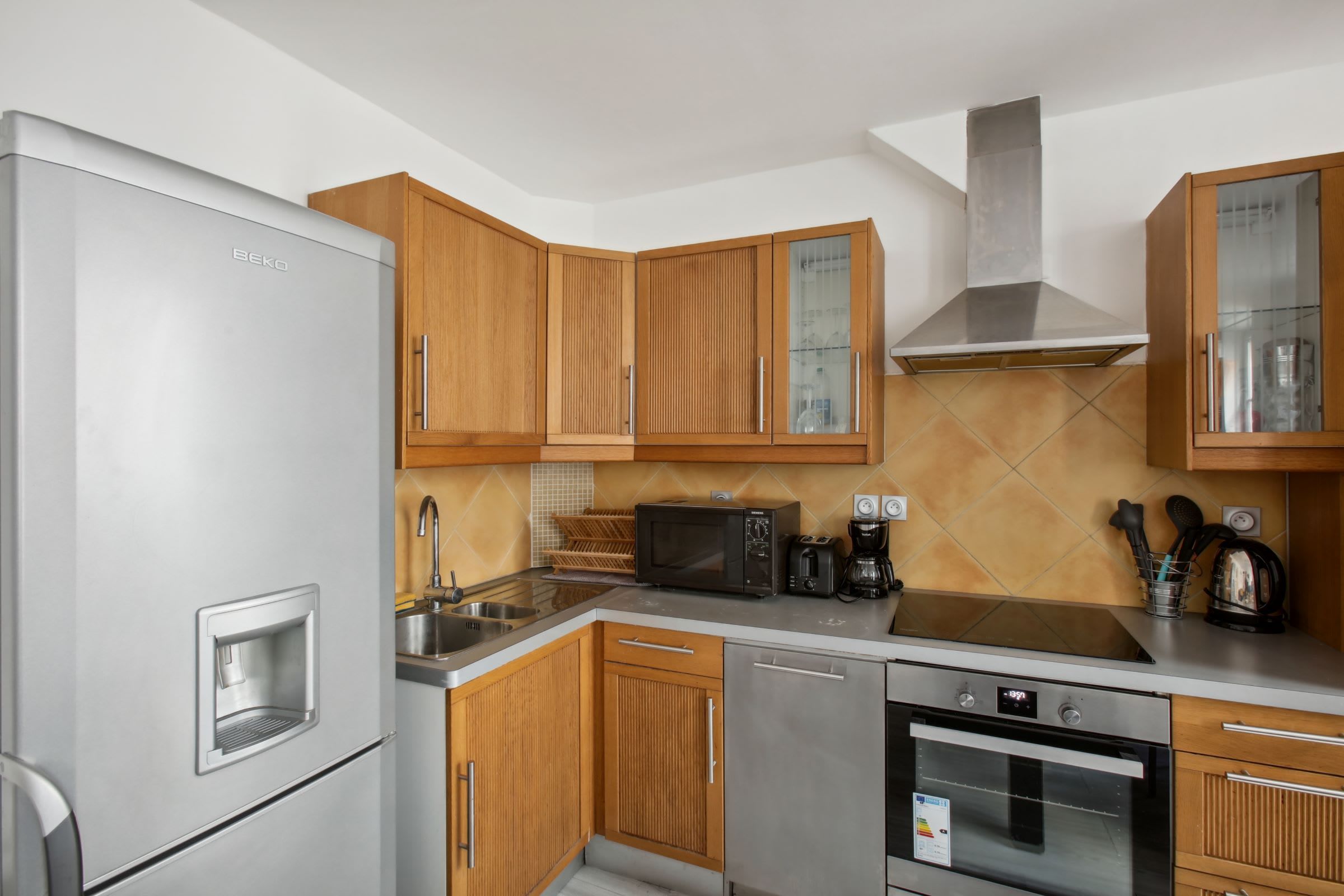 Una cucina moderna con mobili in legno, un frigorifero in acciaio inossidabile, un forno a microonde, una macchina da caffè e un forno.