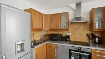 Una cucina moderna con mobili in legno, un frigorifero in acciaio inossidabile, un forno a microonde, una macchina da caffè e un forno.