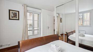 Een hotelkamer met een bed, een stoel, een spiegel en een raam met gordijnen.
