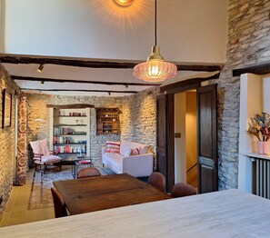 A cozy room with a stone wall, a wooden table, a white sofa, and a hanging light fixture.