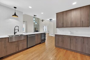 Eine moderne Küche mit Holzschränken, Edelstahlgeräten und einer weißen Küchenrückwand.