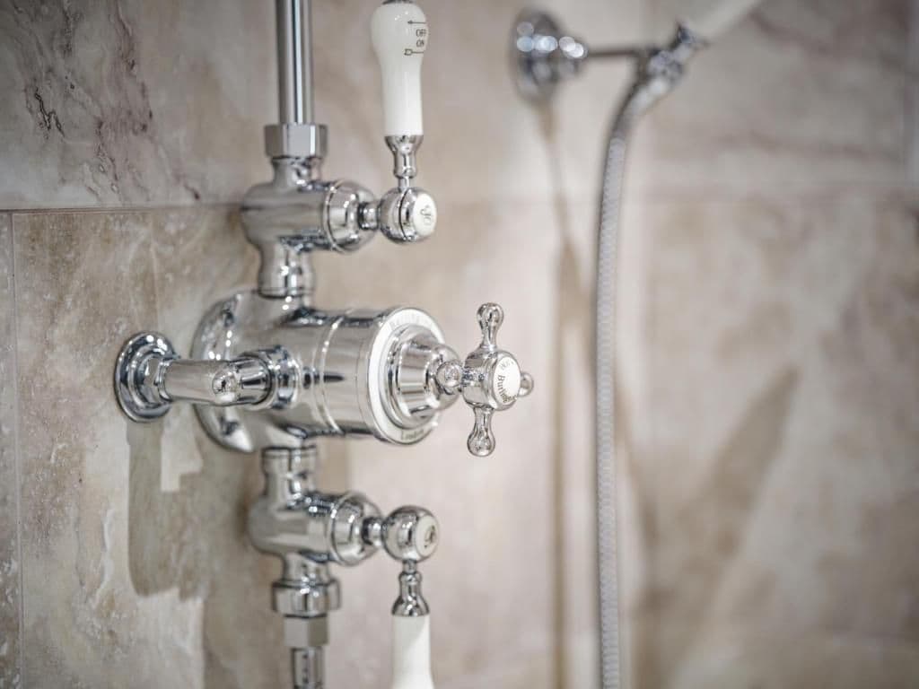 Un baño con ducha, grifo y ducha de mano.