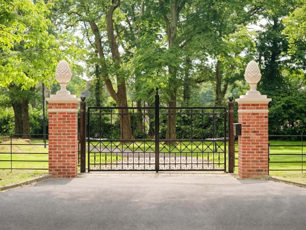 A gated entrance with a brick pillar and a decorative finial.