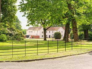 A white building with a brick foundation, surrounded by a well-maintained lawn and a metal fence. - Tyrrells Park (Christchurch)