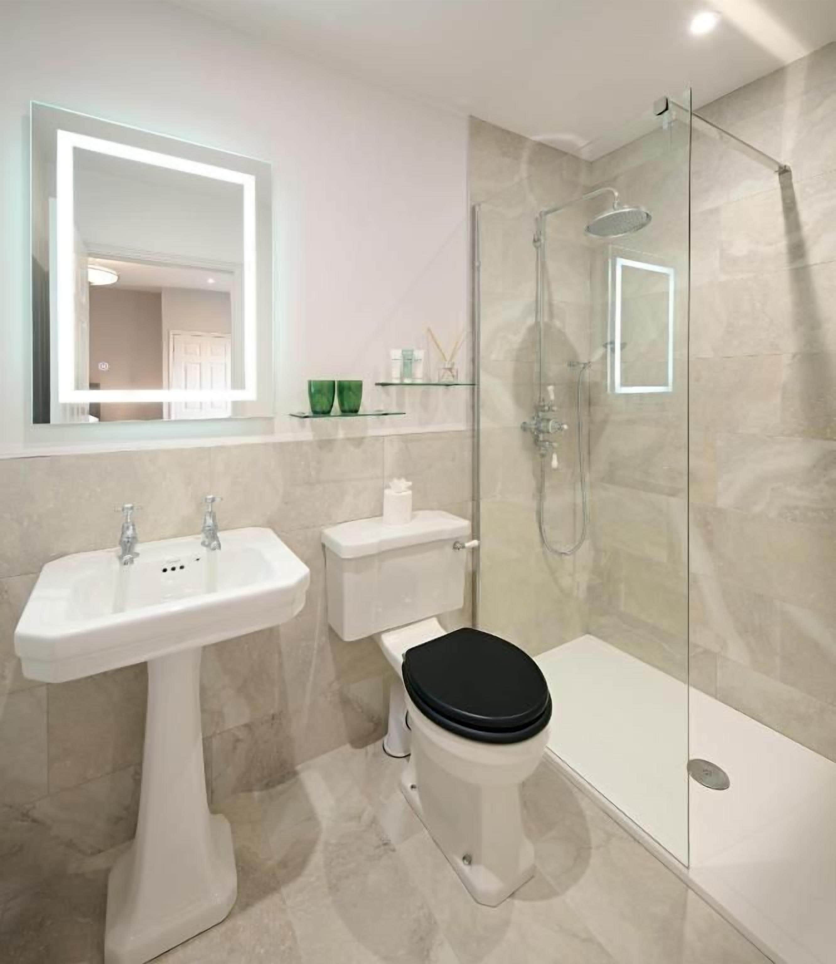 A modern bathroom with a glass-enclosed shower, a white sink, and a toilet.