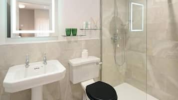 A modern bathroom with a glass-enclosed shower, a white sink, and a toilet.