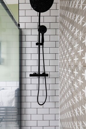 Eine Dusche mit Duschkopf und Schlauch, an einer weißen Ziegelwand befestigt.