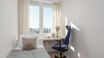 Una camera da letto con un letto, una scrivania, una sedia e una finestra con tende.