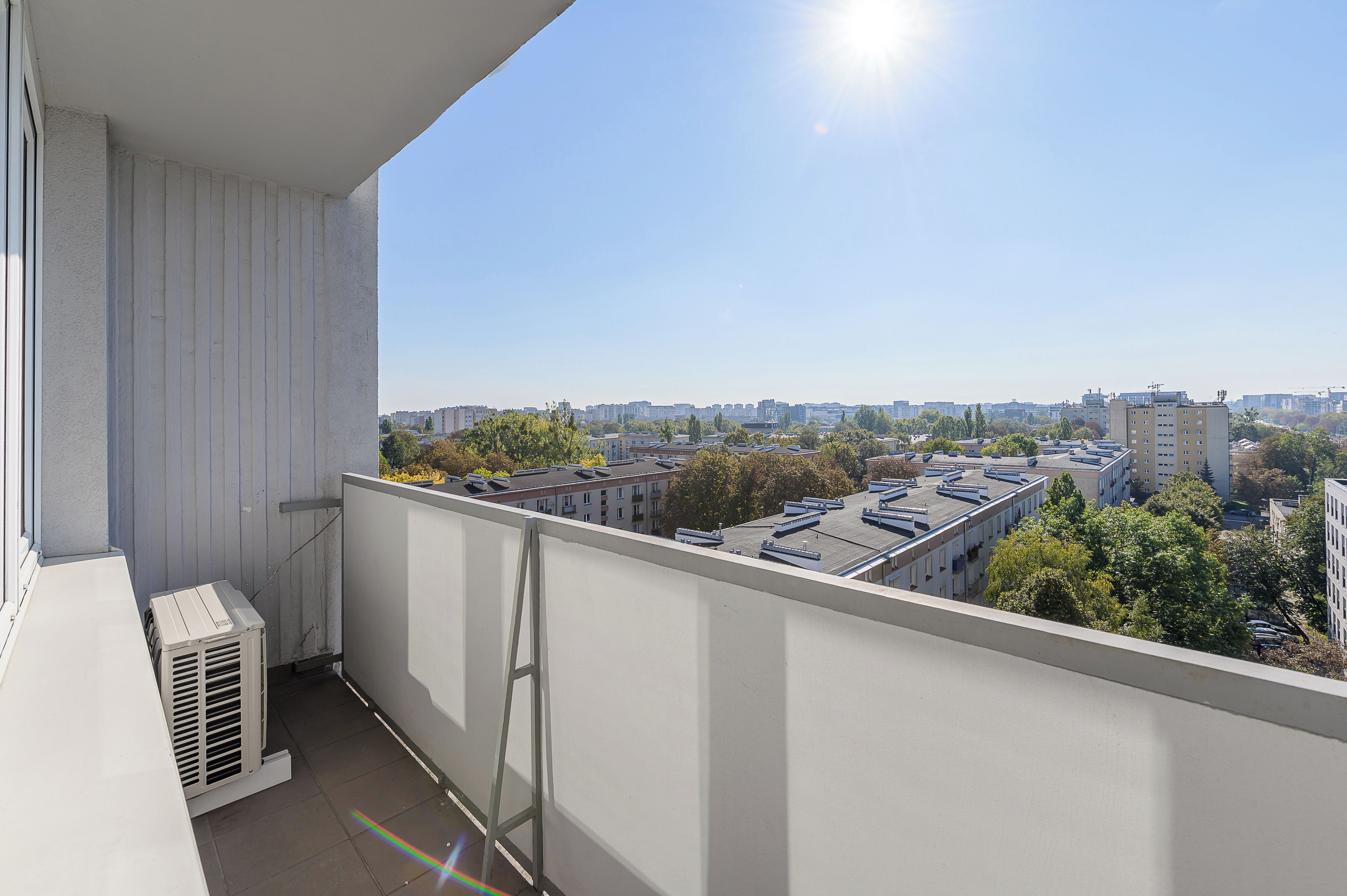 Un balcone con vista su un paesaggio urbano, con edifici e alberi.