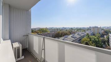 Un balcone con vista su un paesaggio urbano, con edifici e alberi.