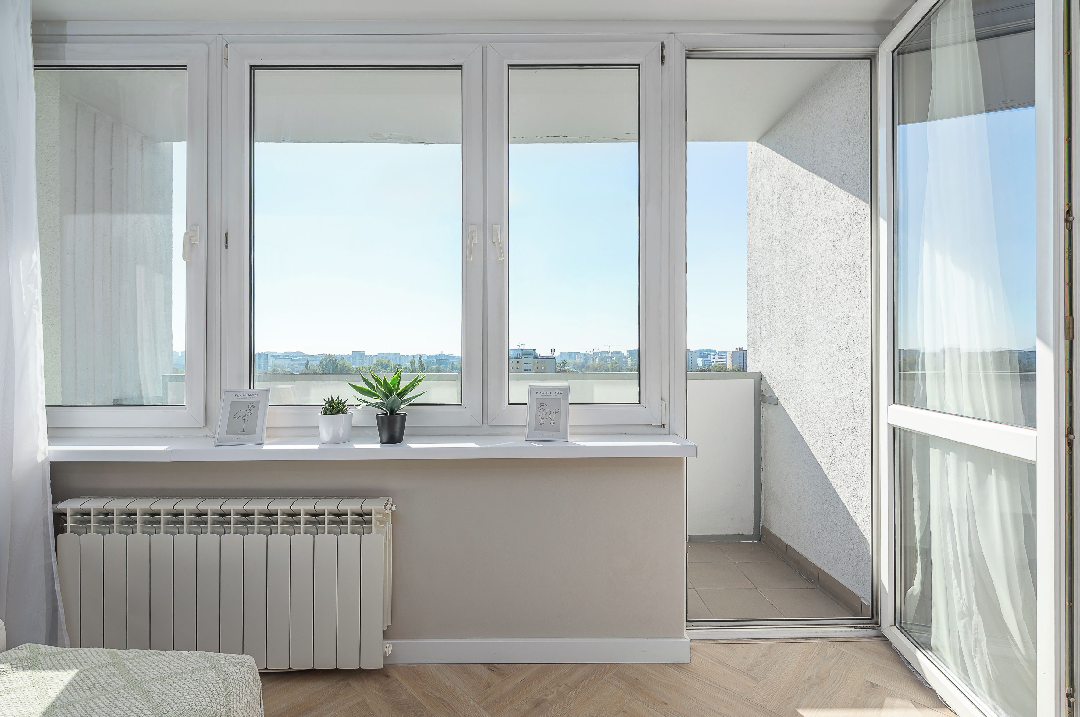 Un balcone con tre finestre, un termosifone e una pianta in vaso.