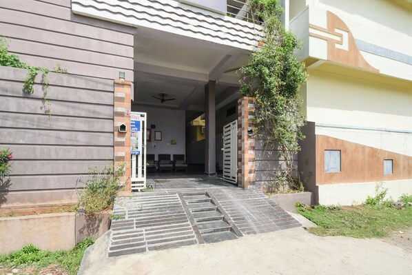 A building entrance with a gated driveway, a mailbox, and a small outdoor seating area.