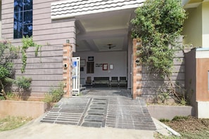 A building entrance with a tiled pathway leading to a reception area with a bench and a signboard. - Hotel O De Alphabet Home Stays NTPC  (Ramagundam)