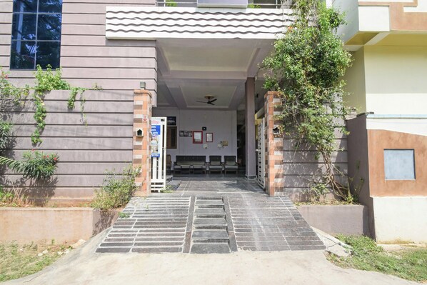 A building entrance with a tiled pathway leading to a reception area with seating.