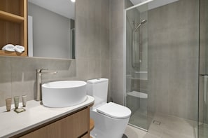 Ein modernes Badezimmer mit einem runden Waschbecken, Toilette und einer Duschkabine.
