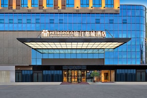 Een hotelentree met een moderne gevel, grote glasramen en een opvallend bord.