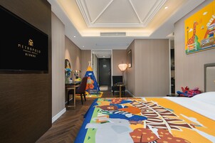 A hotel room with a large bed, a desk, a chair, a TV, and a door leading to another room.