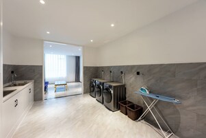 Un moderno cuarto de lavandería con lavadora, secadora y plancha.