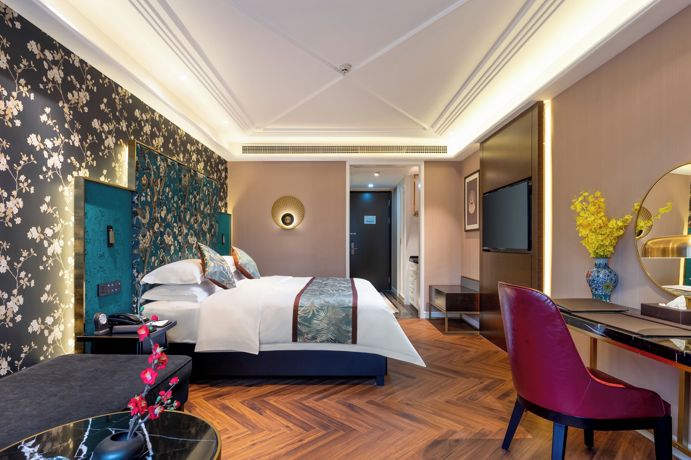 A hotel room with a bed, a desk, a chair, a TV, and a bathroom door.