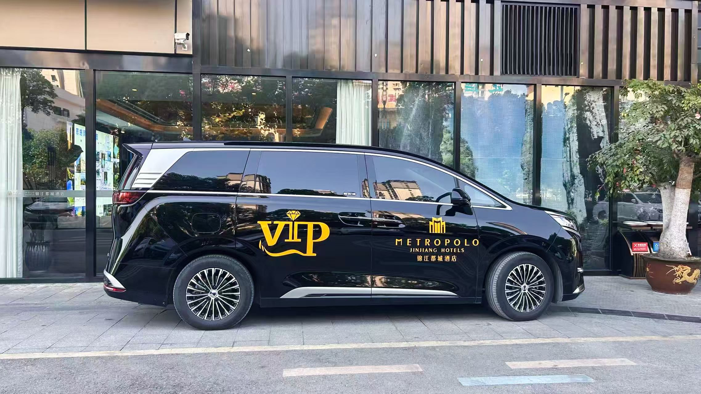 A black car with 'VIP METROPOLO JINJIANG HOTELS' branding parked in front of a building with large windows.