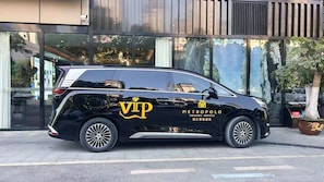 Un cotxe negre amb la marca 'VIP METROPOLO JINJIANG HOTELS' estacionat davant d'un edifici amb grans finestres.
