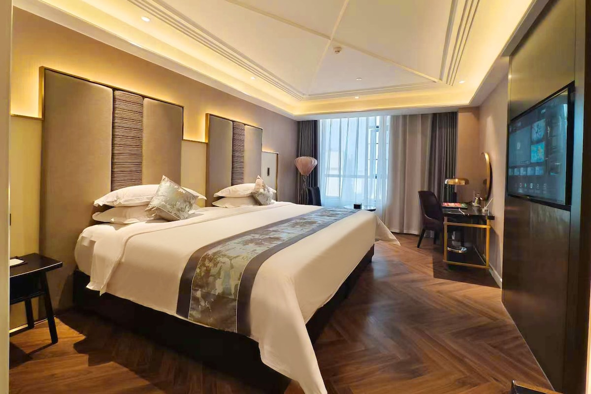 A modern hotel room with a large bed, a desk, and a television.