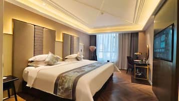 A modern hotel room with a large bed, a desk, and a television.