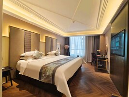 Habitación de hotel moderna con una cama grande, un escritorio y un televisor.