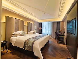 A modern hotel room with a large bed, a desk, and a television.