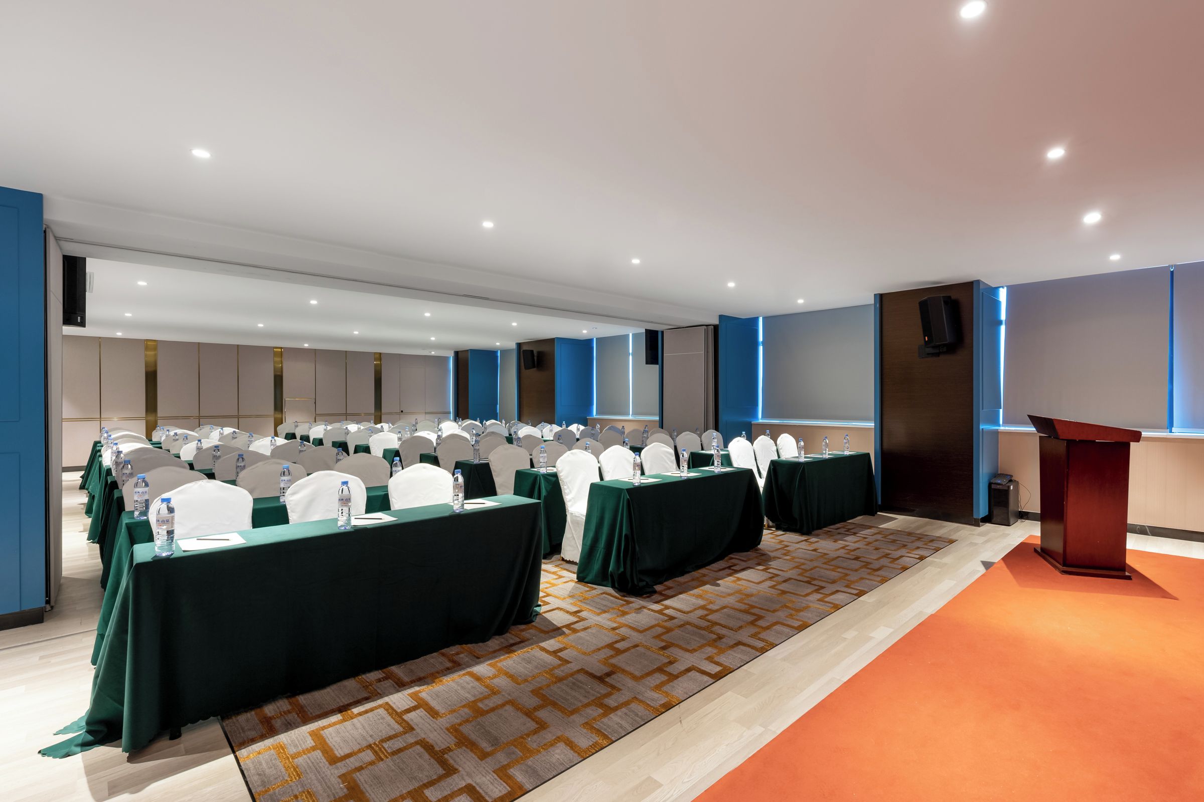 A conference room with rows of tables, chairs, and a podium.