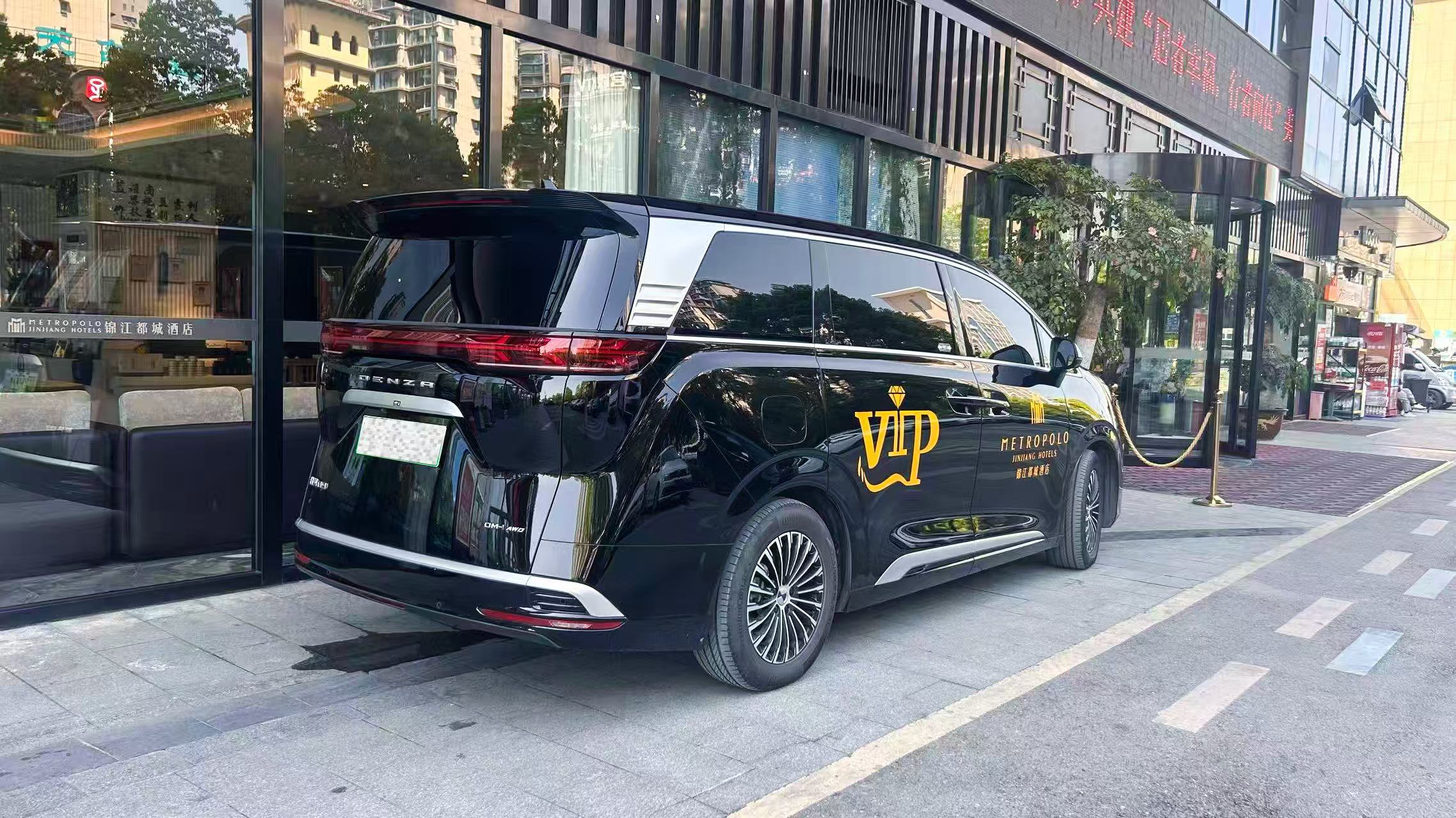 Un SUV negro estacionado frente a un edificio con un letrero que dice 'METROPOLO JINJIANG HOTELS'.