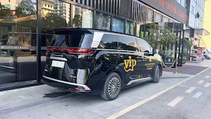 Een zwarte SUV geparkeerd voor een gebouw met een bord waarop staat 'METROPOLO JINJIANG HOTELS'.