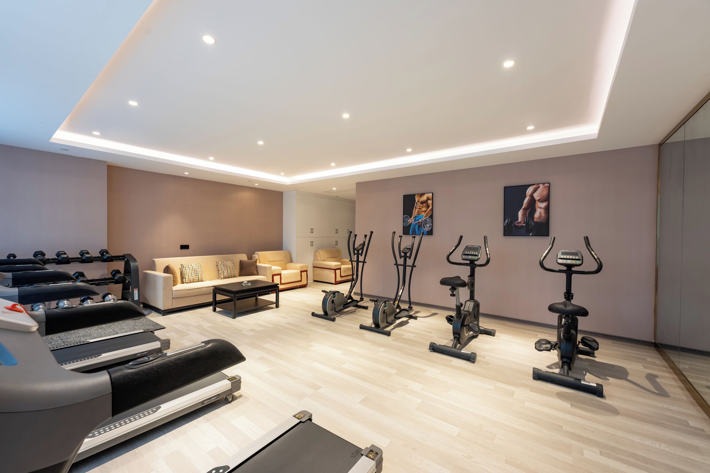 A modern home gym with various exercise equipment, a sofa, and a coffee table.