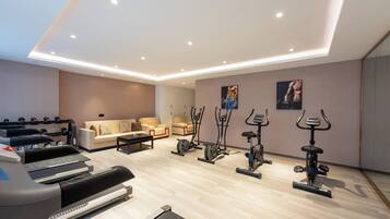 A modern home gym with various exercise equipment, a sofa, and a coffee table.
