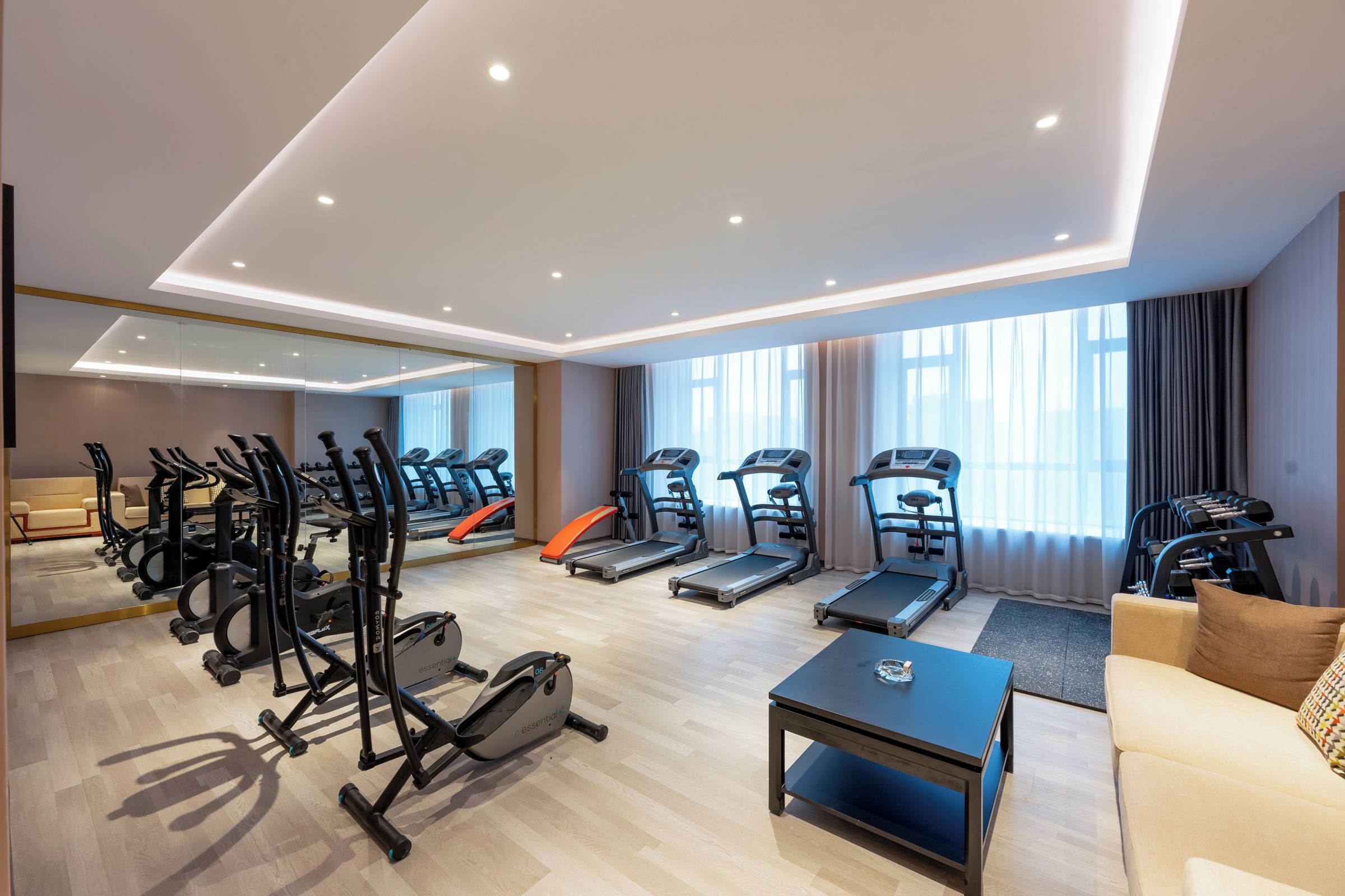 Un gimnasio moderno con cintas de correr, elípticas y pesas libres.