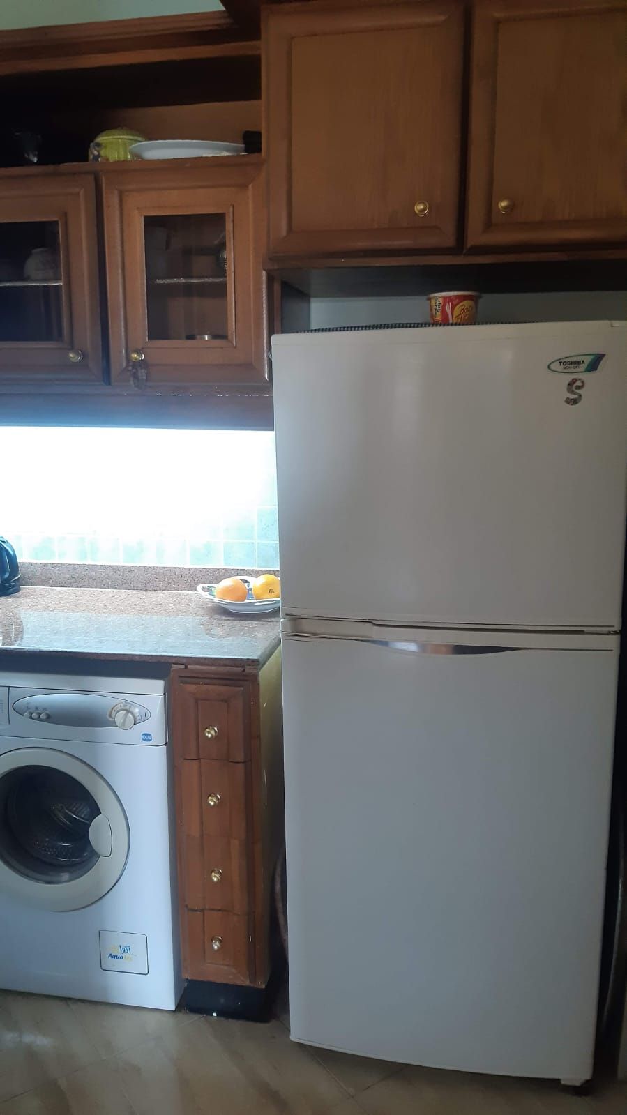 A kitchen with wooden cabinets, a white refrigerator, and a washing machine.