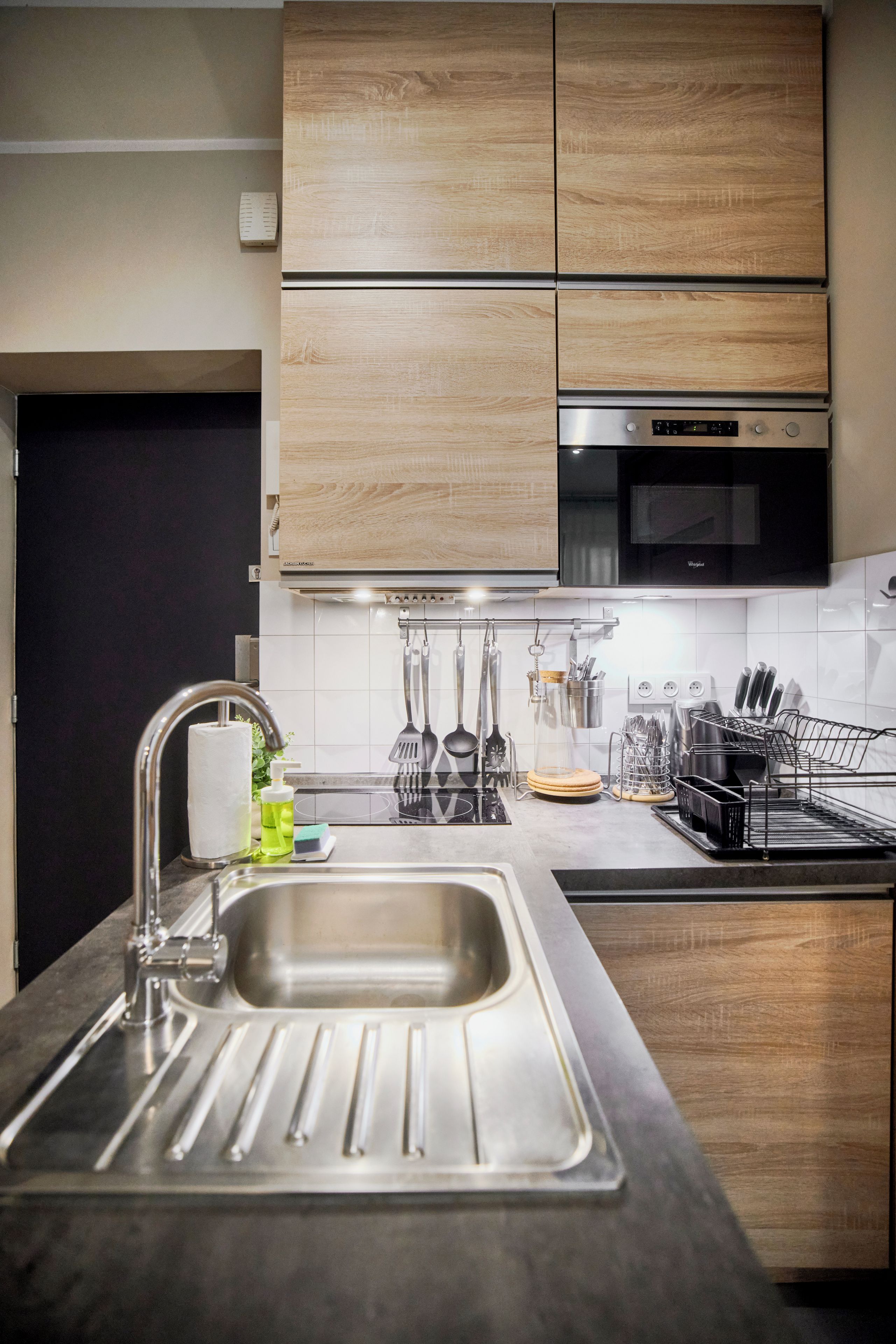 Una cocina moderna con un lavamanos de acero inoxidable, armarios de madera y un horno empotrado.