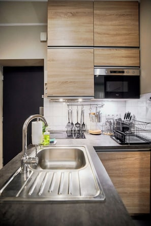 A modern kitchen with a stainless steel sink, wooden cabinets, and a built-in oven. - RentPlanet - Apartamenty Piłsudskiego 41 (Wrocław)