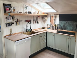 A kitchen with a dishwasher, wooden cabinets, a sink, and a skylight. - 5 Person Holiday Home in Havndal (Havndal)