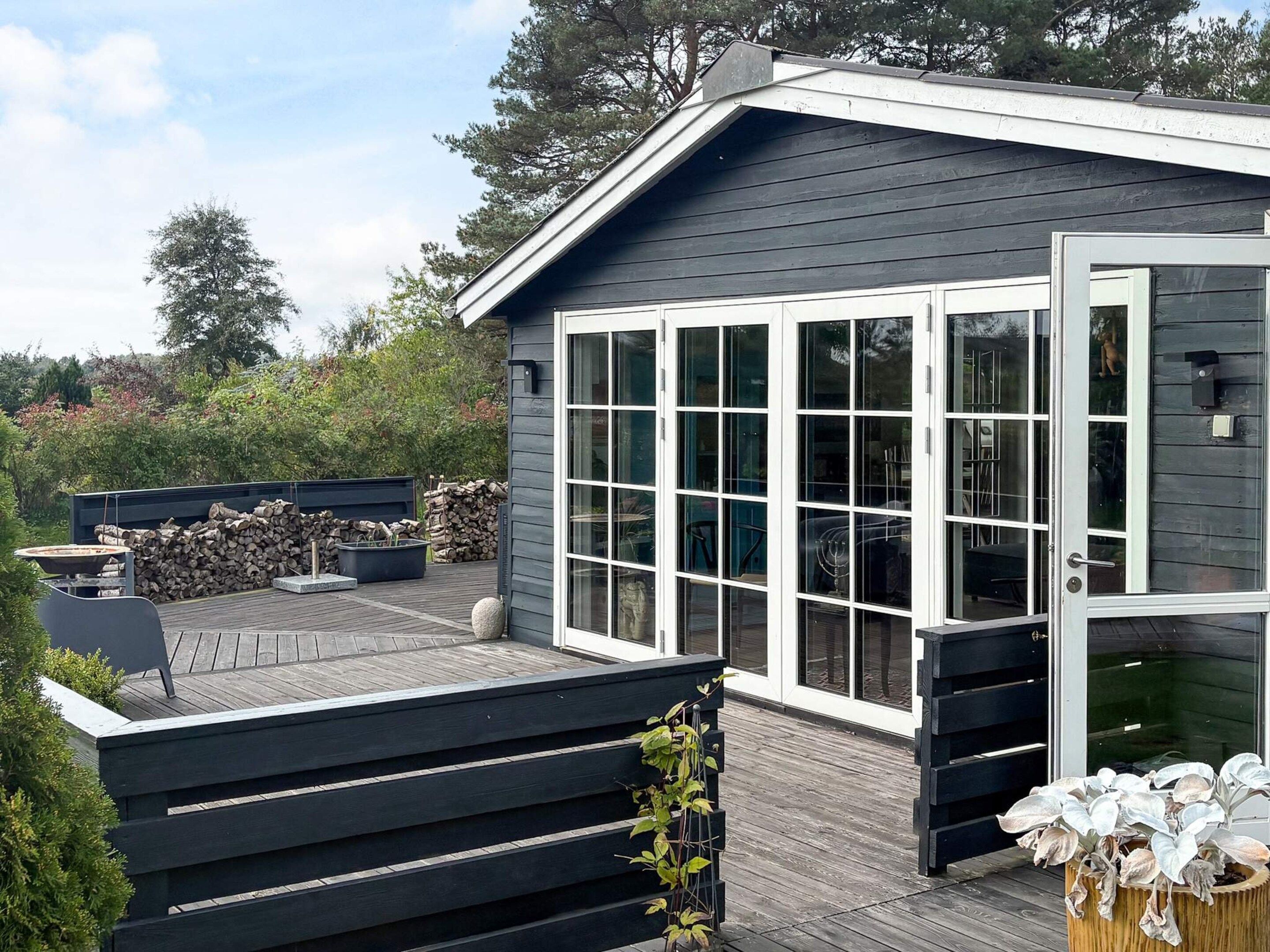 Een modern gebouw met een terras, grote ramen en zitplaatsen buiten.