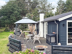 A deck with outdoor furniture, a fire pit, and a covered area with a table and chairs. - 5 Person Holiday Home in Havndal (Havndal)