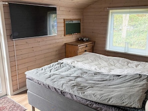 A bedroom with a bed, a wooden dresser, a blackboard, and a window with blinds. - 5 Person Holiday Home in Havndal (Havndal)
