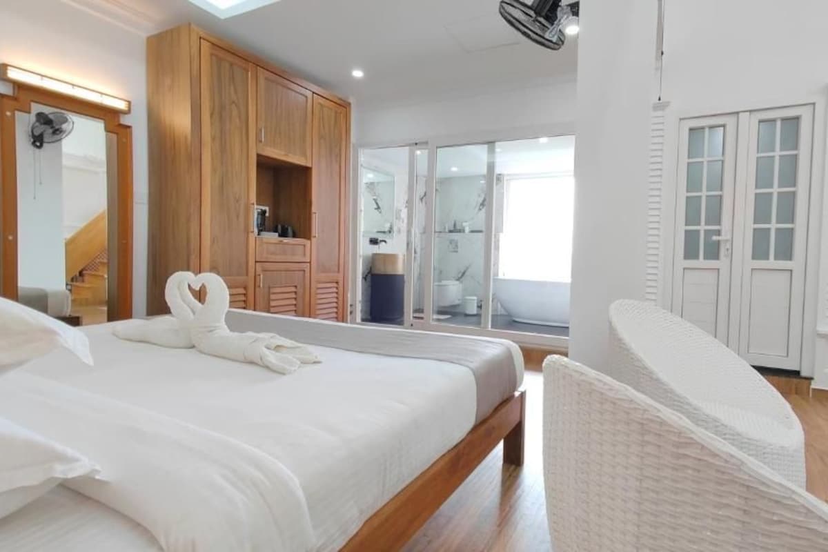 Un dormitorio con una cama grande, armario de madera y puerta corrediza de vidrio que da a un balcón.