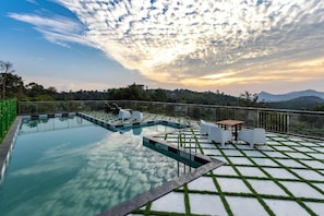 Una piscina con vistas a montañas y al atardecer.