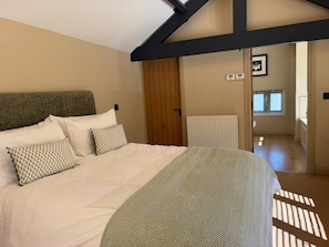 Ein Schlafzimmer mit einem Bett, einer Holztür, einem Heizkörper und einem Fenster.