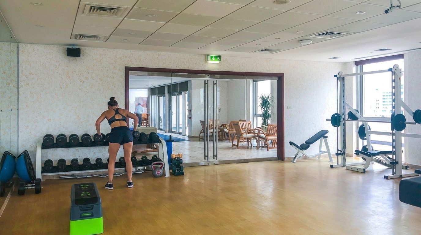 Een fitnessruimte met trainingsapparatuur, een halterbank en een spiegel.