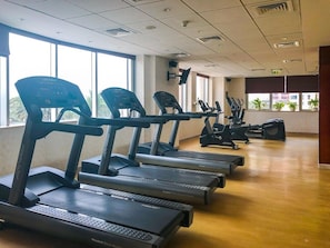 A gym with multiple treadmills, exercise bikes, and a wooden floor. - Vogue | Emaar Tower Al Rigga near Metro Station  (Dubai)